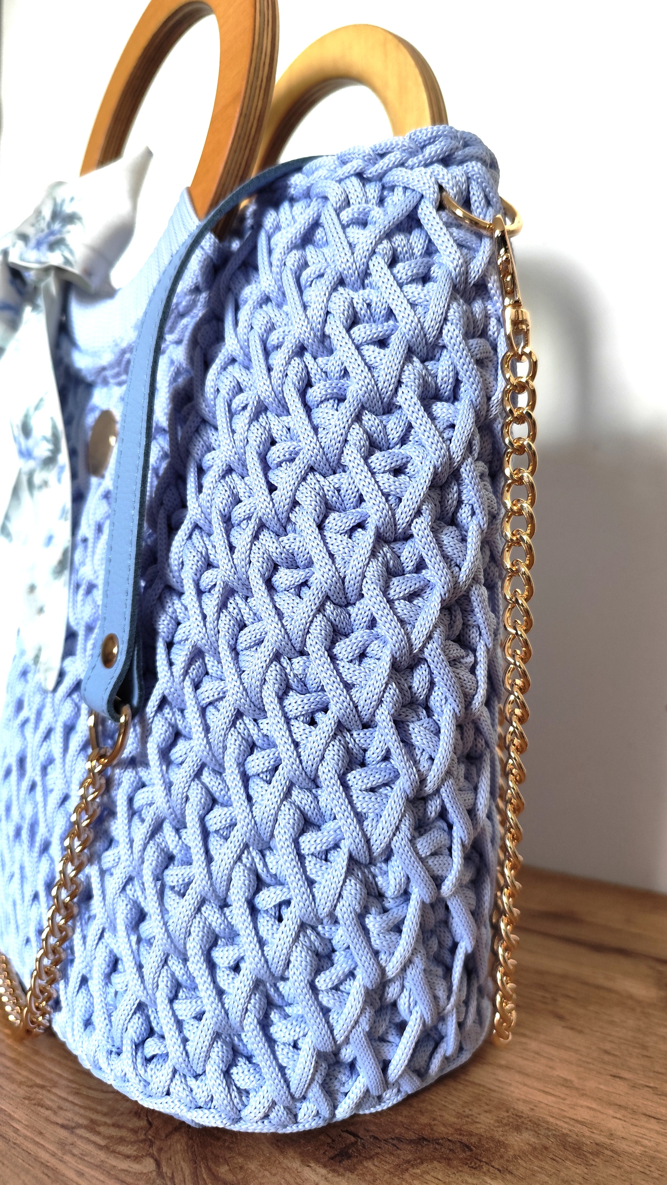 Detal torebki ze sznurka z paskiem łańcuszkowym w kolorze złota i dodatkiem skórzanym w kolorze lodowego błękitu. 